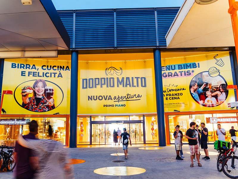 Doppio Malto fa cinquina a Milano: apertura al Bicocca Village L'ingresso del Bicocca Village che annuncia la nuova apertura di Doppio Malto